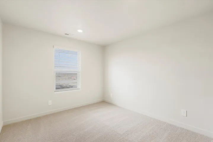 Wall-to-wall carpeting and a single window with blinds