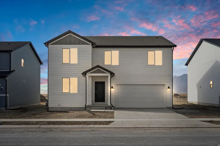 Two-story residence featuring light-toned siding, a dark-toned roof, and an integrated two-car garage