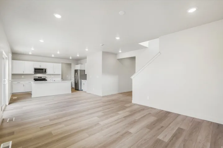 Open-concept living space with wood-finish flooring, recessed lighting, and a modern kitchen