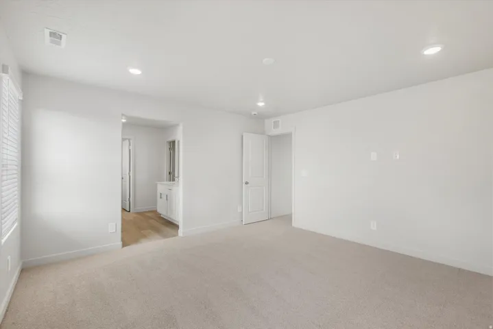 Carpeted flooring, recessed lighting, white interior doors, and a window with blinds