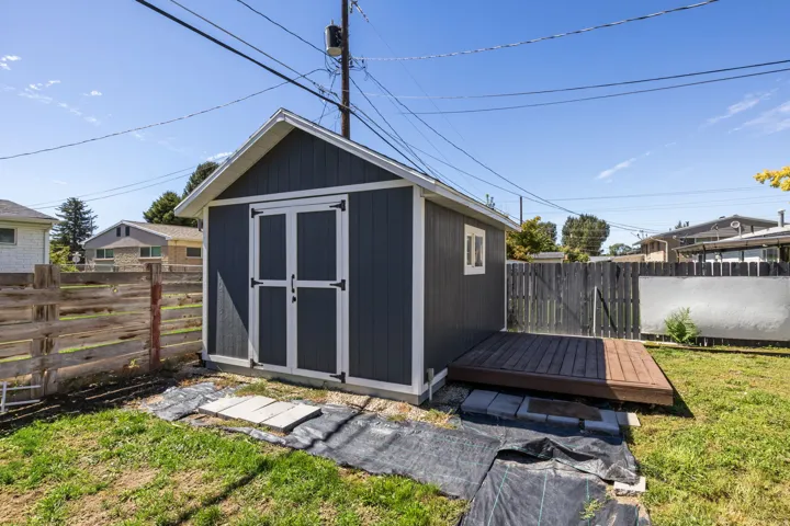 Storage shed with a dark gray exterior, white trim, and double doors