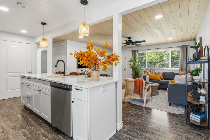 Kitchen island featuring white cabinetry, a built-in dishwasher, and a black faucet