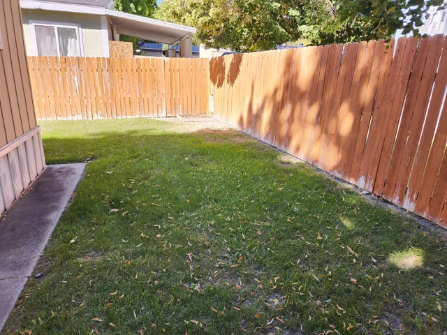 Fenced yard with a grassy area and concrete walkway