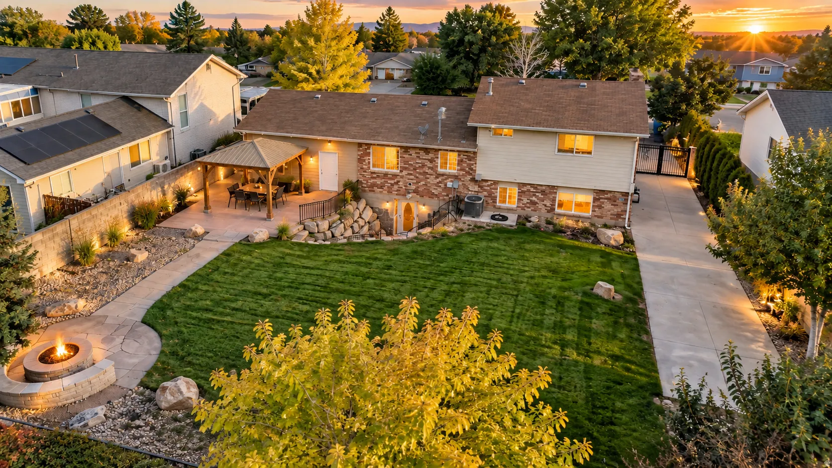 Expansive backyard featuring a stone fire pit, paved patio with a pergola, and manicured lawn