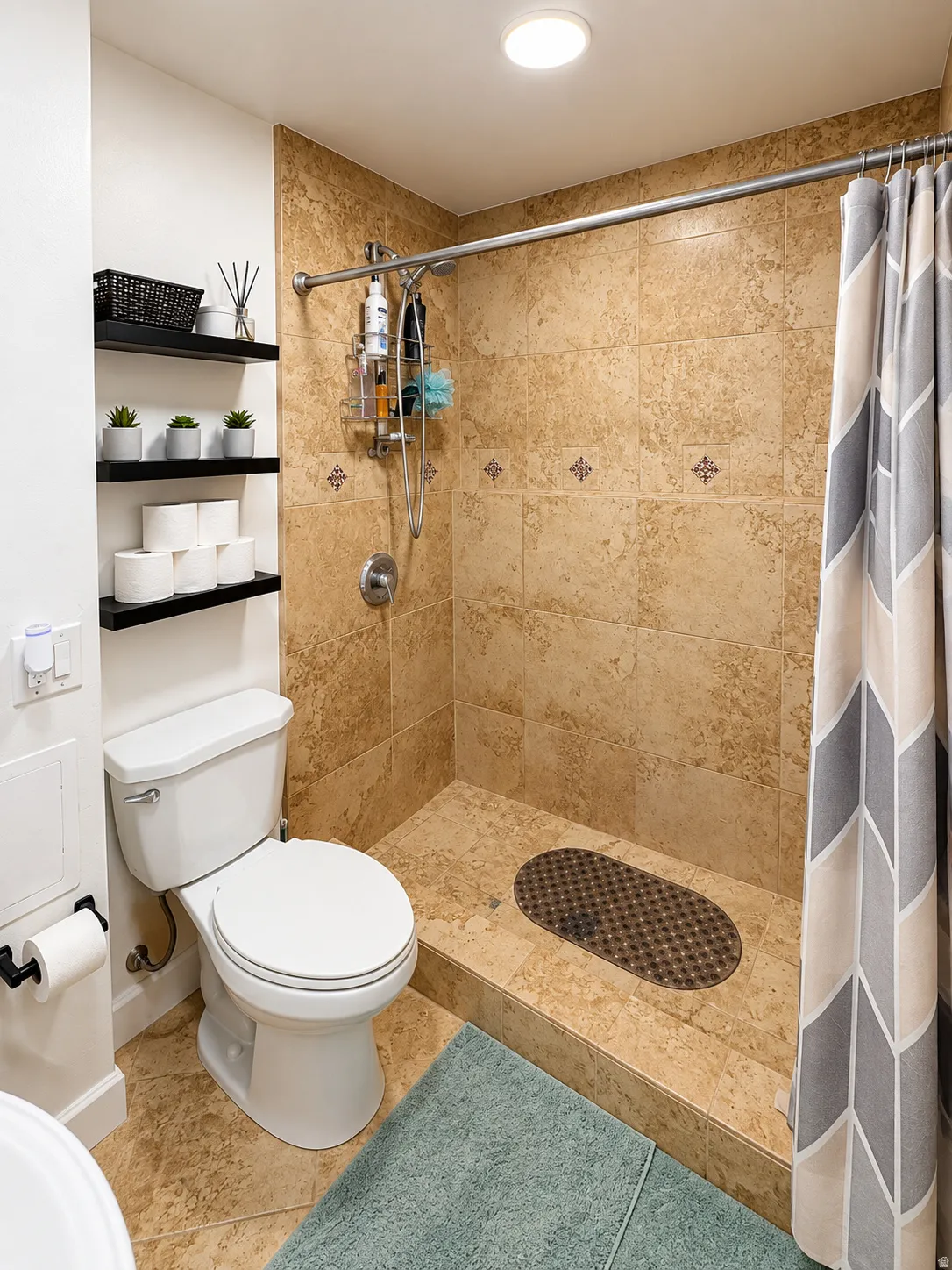 Walk-in shower with natural stone tile surround and floor, accented by decorative tile inserts