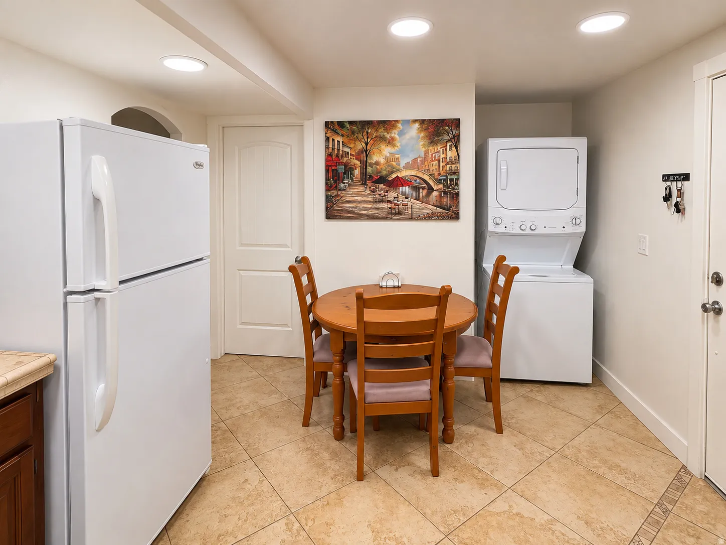 Integrated kitchen appliances, stacked laundry machines, recessed ceiling lighting, and tile flooring