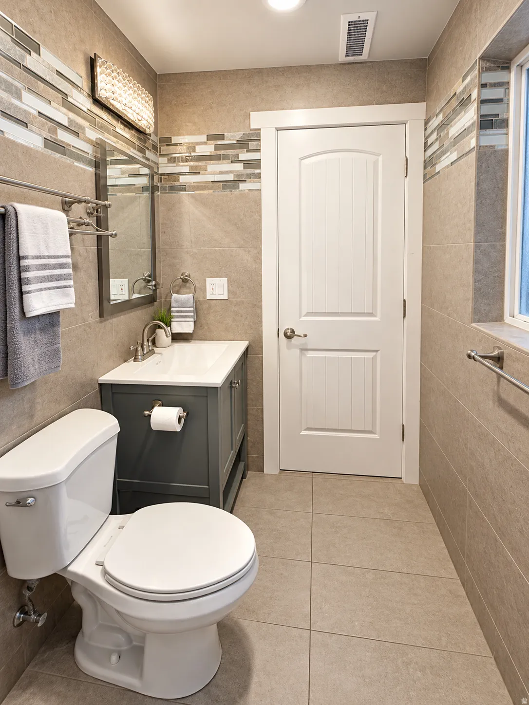 Bathroom 2, Full-height tile walls with a decorative mosaic accent band, a white vanity with a rectangular basin, and neutral-toned floor tiling