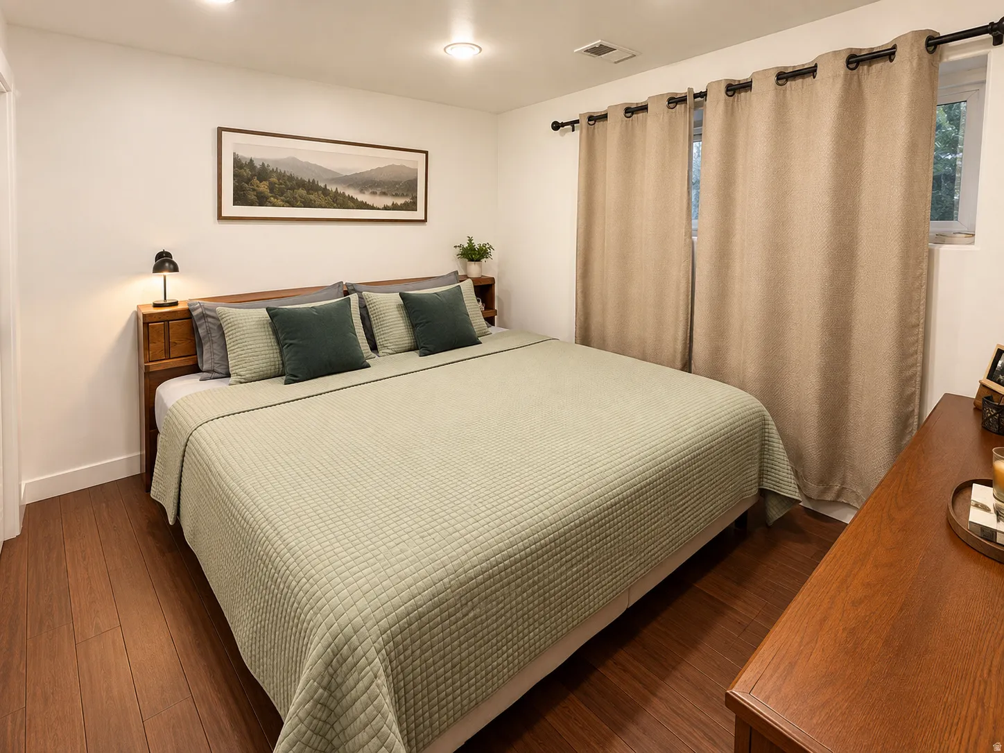 Recessed ceiling lighting, wood-finish flooring, two windows with curtain rods, and a wood headboard with integrated shelving