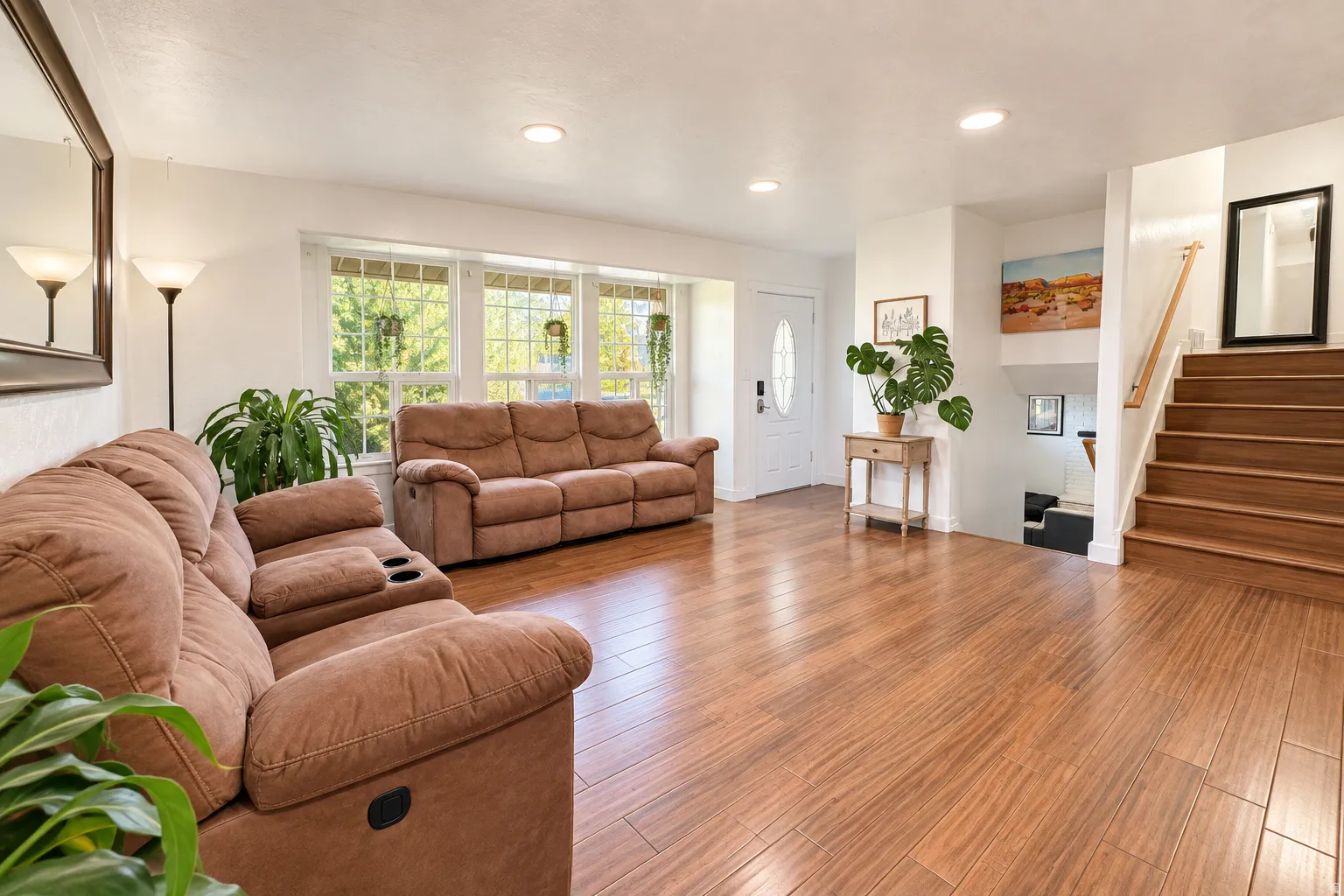 Wood-finish flooring throughout, recessed lighting, white walls, and a front entry door with decorative glass