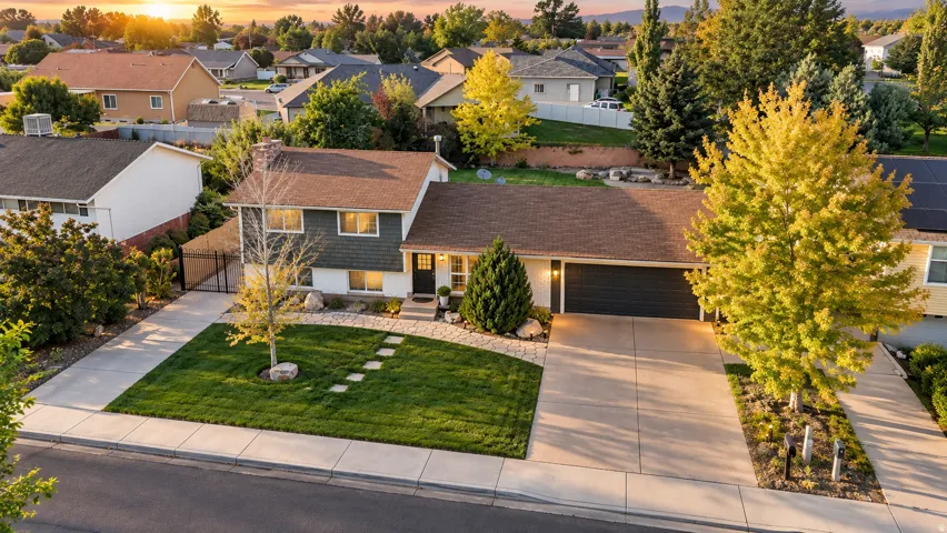 Split-level residence featuring a two-car garage, concrete driveway, and front lawn with stepping stones