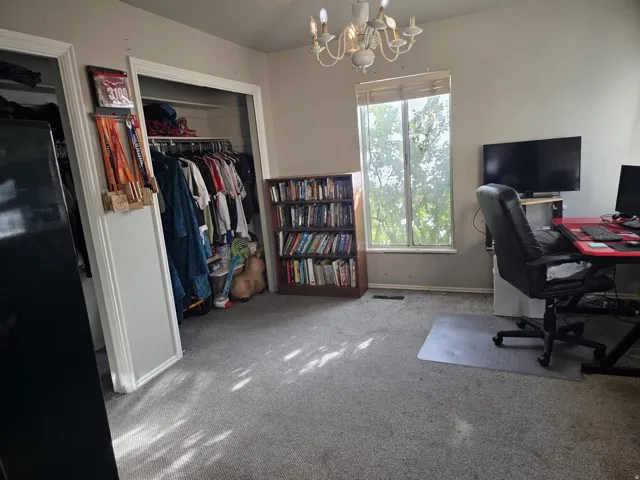 Room with light-colored carpeting, a multi-pane window, and a white chandelier light fixture