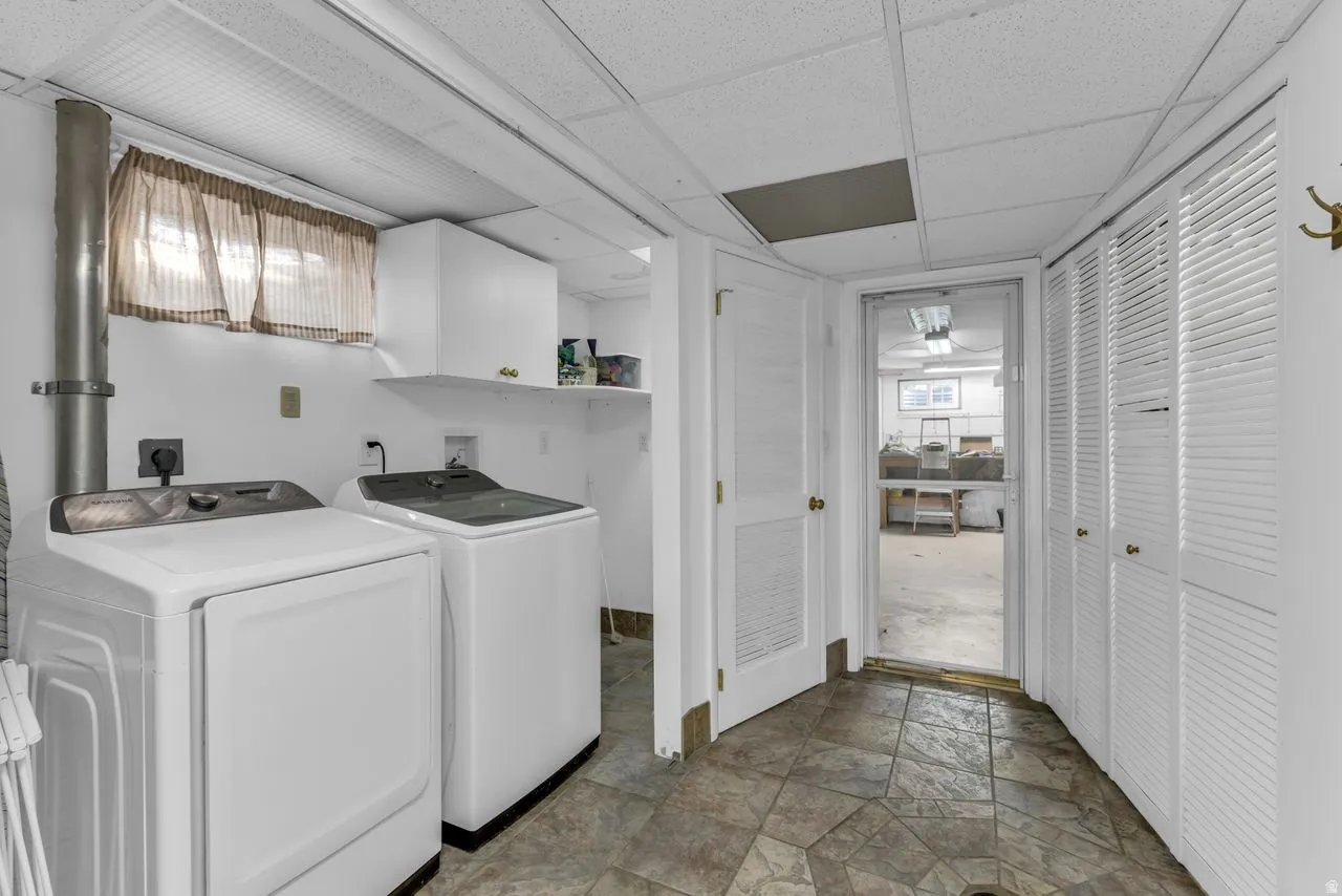 Laundry area featuring patterned tile flooring, built-in shelving, white cabinetry, and louvered closet doors