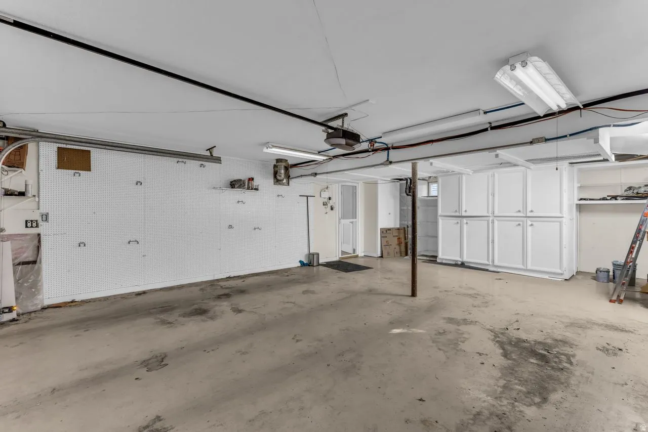 Spacious garage featuring a concrete floor, built-in white cabinetry, and overhead fluorescent lighting