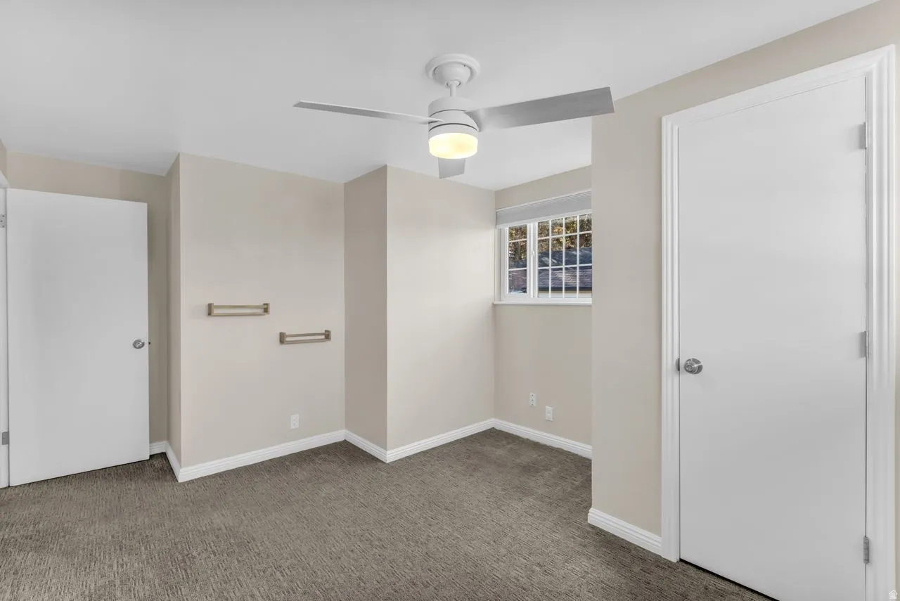 Wall-to-wall carpeting, ceiling fan with integrated lighting, and a window with blinds