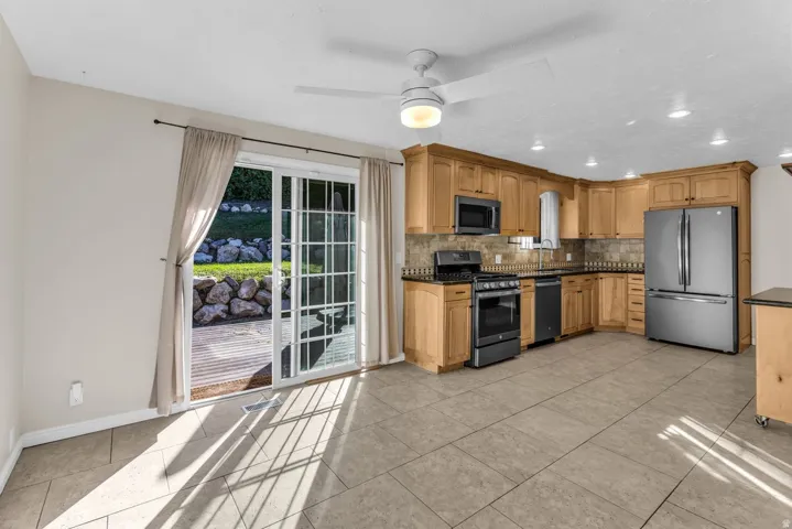 Kitchen featuring wood cabinetry, stainless steel appliances, and a tile backsplash