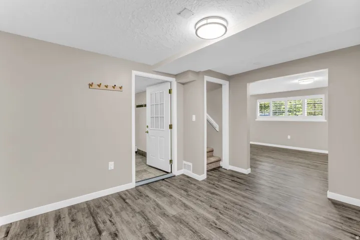 Wood-finish flooring, neutral wall tones, recessed lighting, and a white paneled door