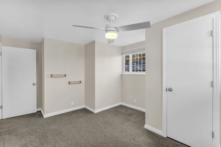 Wall-to-wall carpeting, ceiling fan with integrated lighting, and a window with blinds