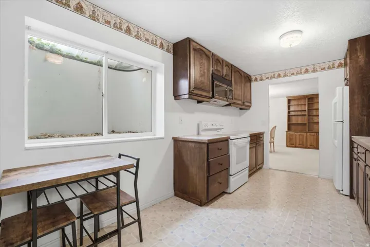 Wood-finish cabinetry and built-in microwave, complemented by white appliances