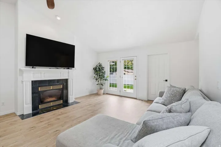 Living area featuring a fireplace with a decorative mantel and dark stone surround, wood-finish flooring, and double glass-paned doors