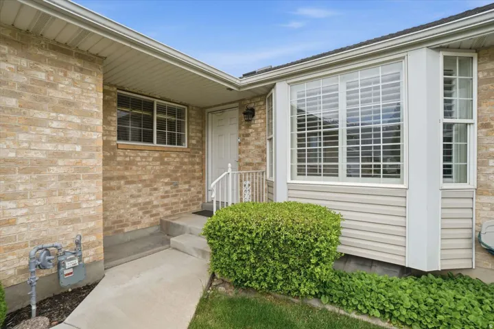 Brick exterior with a prominent bay window, concrete entryway, and mature shrubs