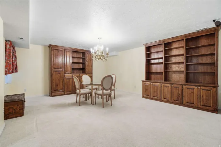 Built-in wood shelving and cabinetry with crown molding, and a central chandelier