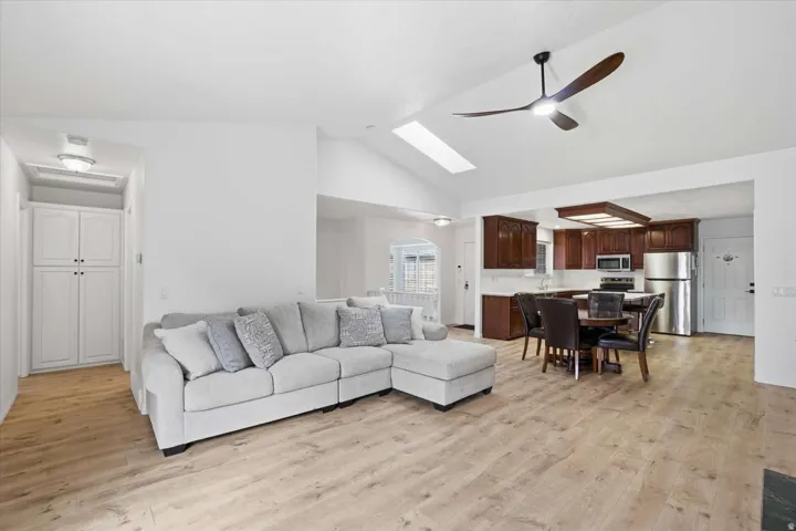 Vaulted ceiling with skylight, wood-finish flooring, kitchen with wood cabinetry and stainless steel appliances, built-in storage cabinets