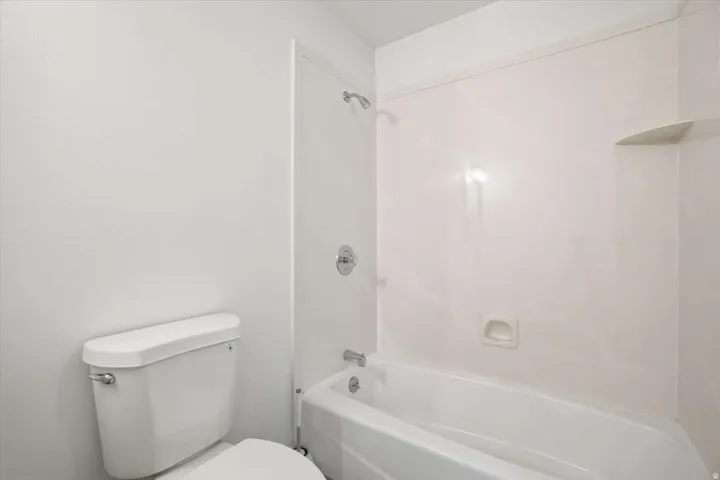 White finish bathtub and shower combination with chrome fixtures