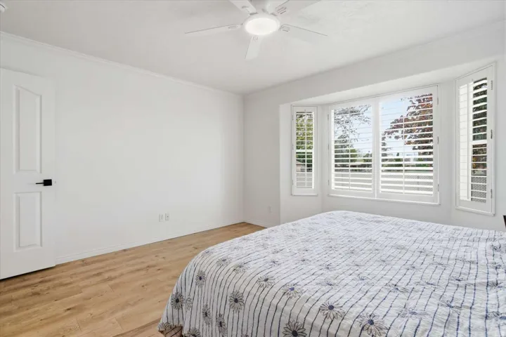 Wood-finish flooring, white walls, and a ceiling fan with light fixture