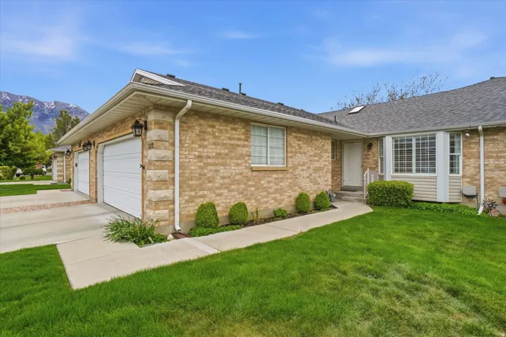 Brick exterior with stone accents, two-car garage, front yard with mature landscaping, and a bay window feature