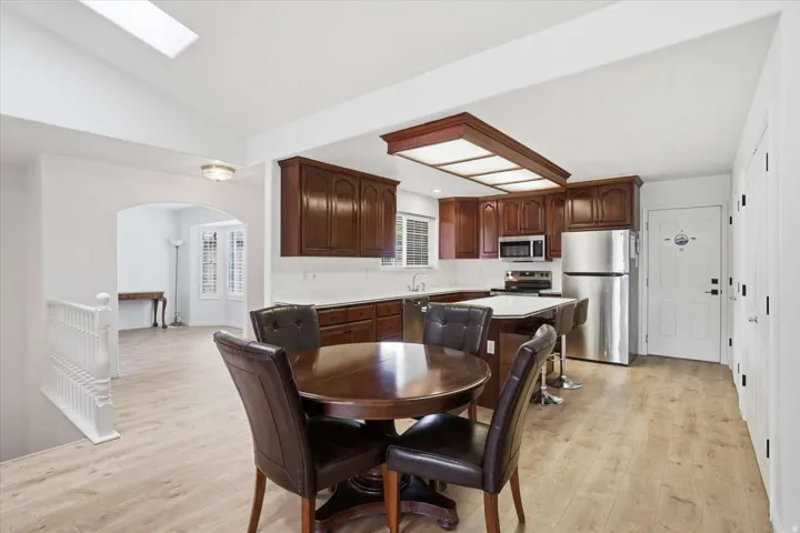 Kitchen featuring dark wood cabinetry, stainless steel appliances, a center island with bar seating, and wood-finish flooring