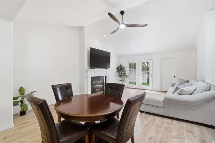 Vaulted ceilings with a ceiling fan, fireplace with a mantel, wood-finish flooring, and French doors