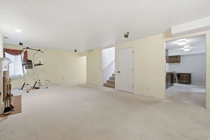 Expansive carpeted area with a fireplace featuring a brick surround, white mantel, and integrated storage