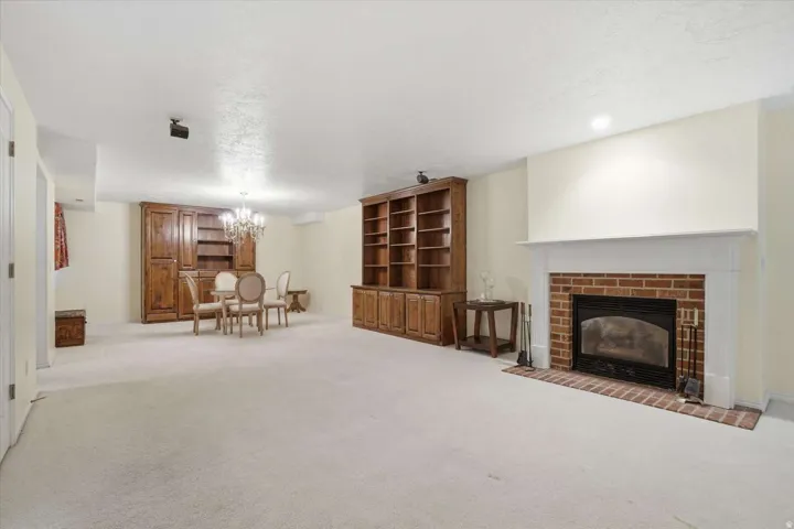 Built-in wooden cabinetry, brick fireplace with white mantel, recessed lighting, and chandelier