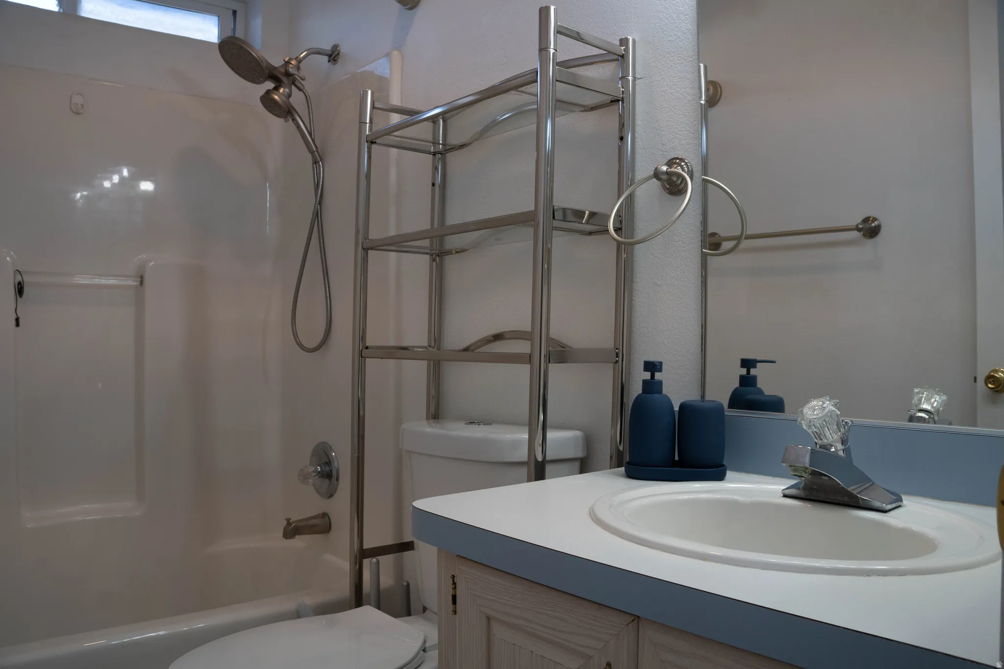 White integrated sink, chrome faucet, wood-finish vanity, and a full-width wall mirror