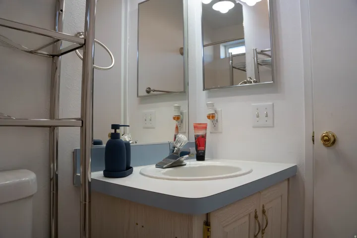 Bathroom vanity with a countertop sink, mirrored medicine cabinet, and overhead light fixture