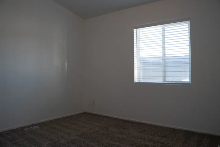 Carpeted flooring, white walls, and a window with blinds