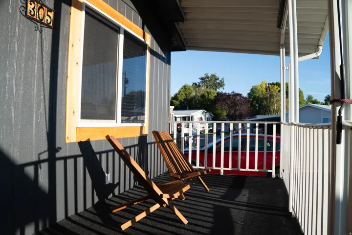 Covered porch with vertical siding, protective railing, and a framed window