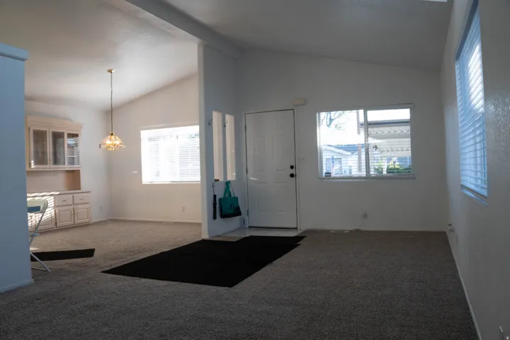 Vaulted ceilings, built-in display cabinetry, pendant lighting, and multiple windows