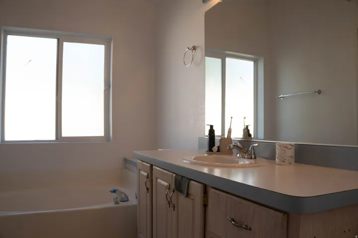 Integrated vanity with an oval sink, chrome faucet, and expansive wall mirror