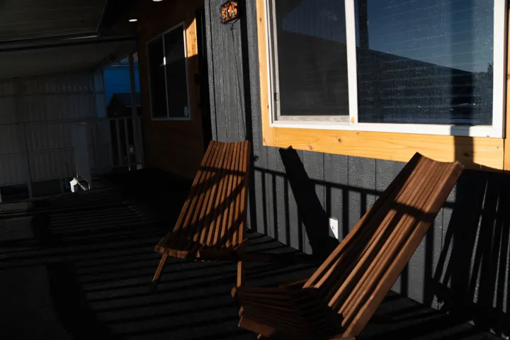 Covered porch area featuring a dark-toned floor and a light wood-paneled wall