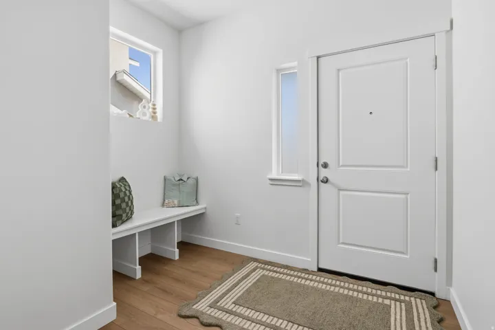 Entryway with a paneled door, wood-finish flooring, and a built-in bench
