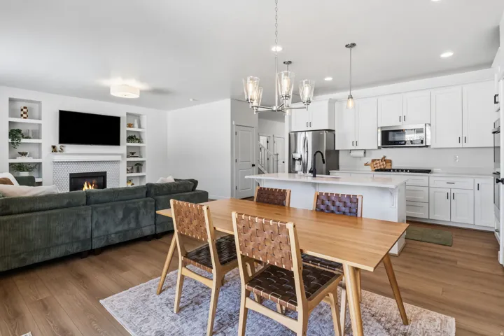Open-concept living space featuring a kitchen with white cabinetry, a center island with pendant lighting, and stainless steel appliances
