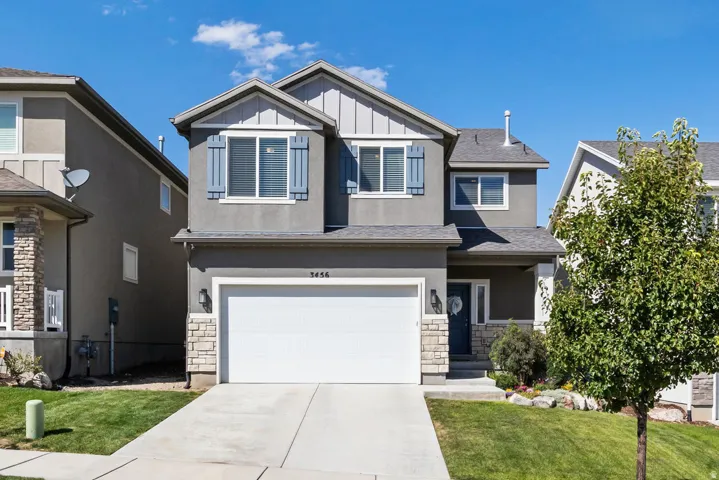 Two-story residence featuring a two-car garage, stone and stucco exterior, and a covered entryway