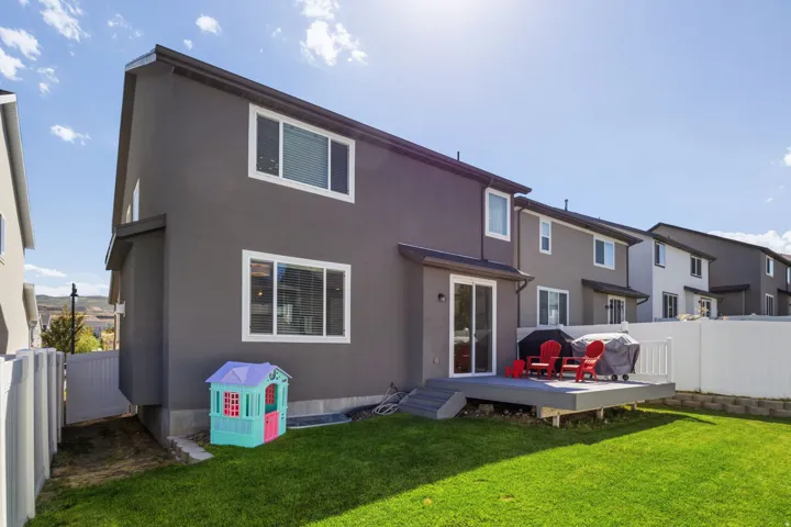 Manicured lawn, exterior with multiple windows, sliding glass door, private deck, and white privacy fencing