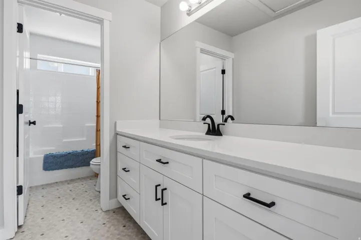 Double vanity with white shaker cabinetry, matte black hardware, and an integrated countertop