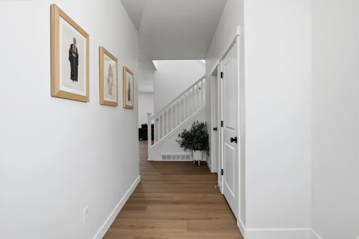 Wood-finish flooring throughout, white interior doors with black hardware, and a white staircase with balusters