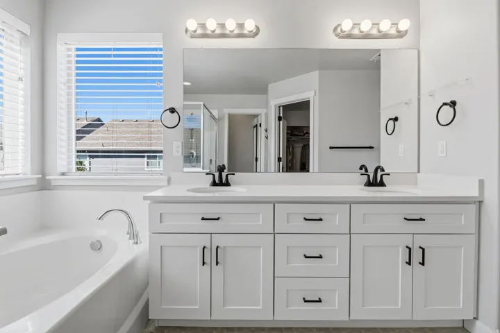 Dual vanity with white shaker cabinetry, quartz countertop, and matte black fixtures