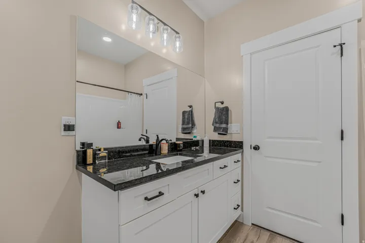 Vanity with dark countertops, white cabinetry, undermount sink, and black hardware
