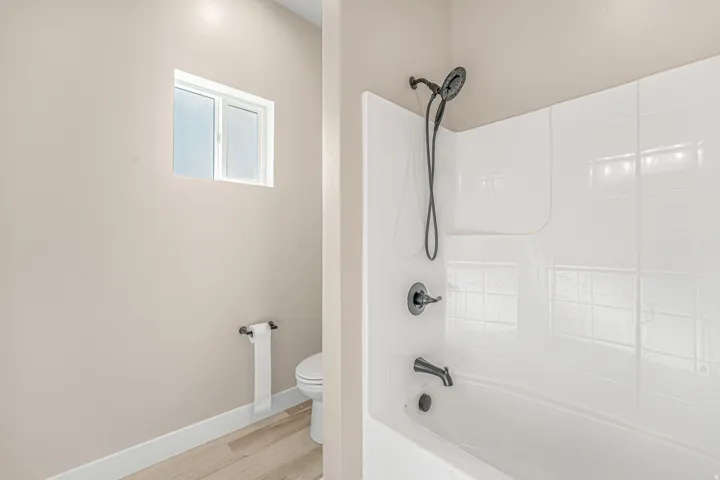 White bathtub and shower combination with dark bronze fixtures