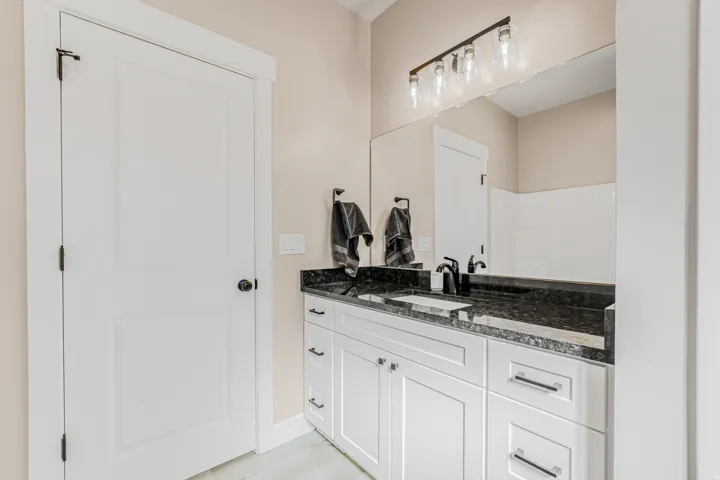 White vanity with dark stone countertop, integrated rectangular sink, and matte black faucet